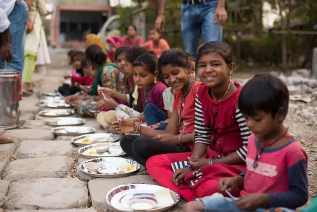 Children sitting in a row enjoying a meal
