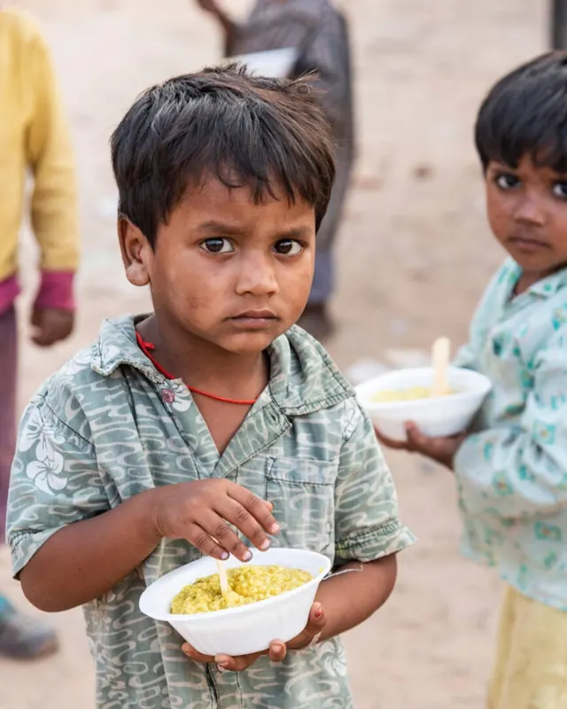 A young boy holding a bowl of freshly served food
