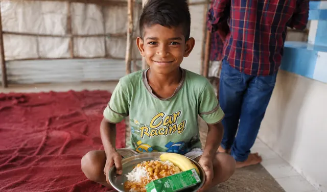 A smiling boy holding a plate of food